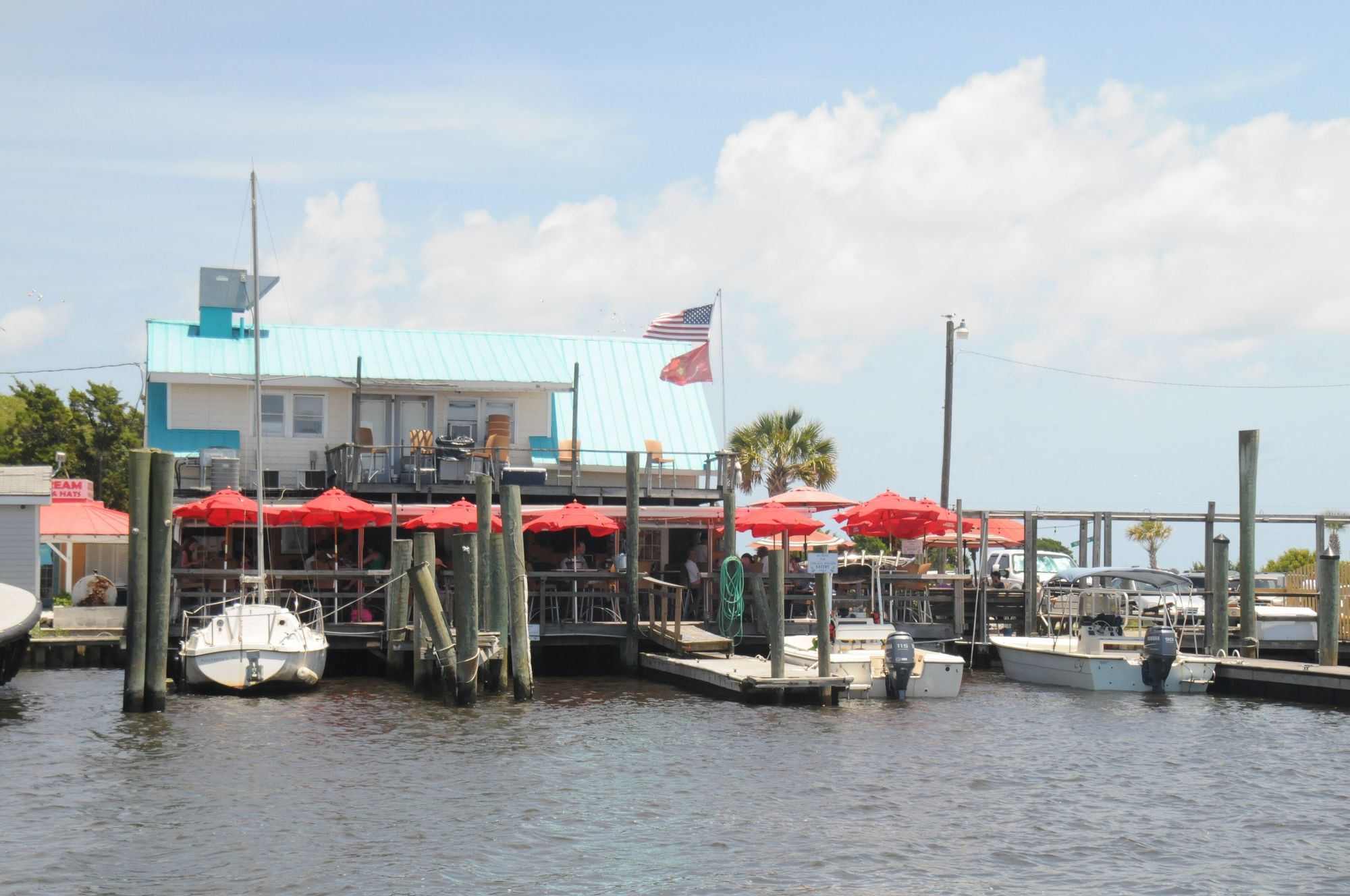 Boats tied up at waterfront restaurants on the Southport Yacht Basin under a blue summer sky